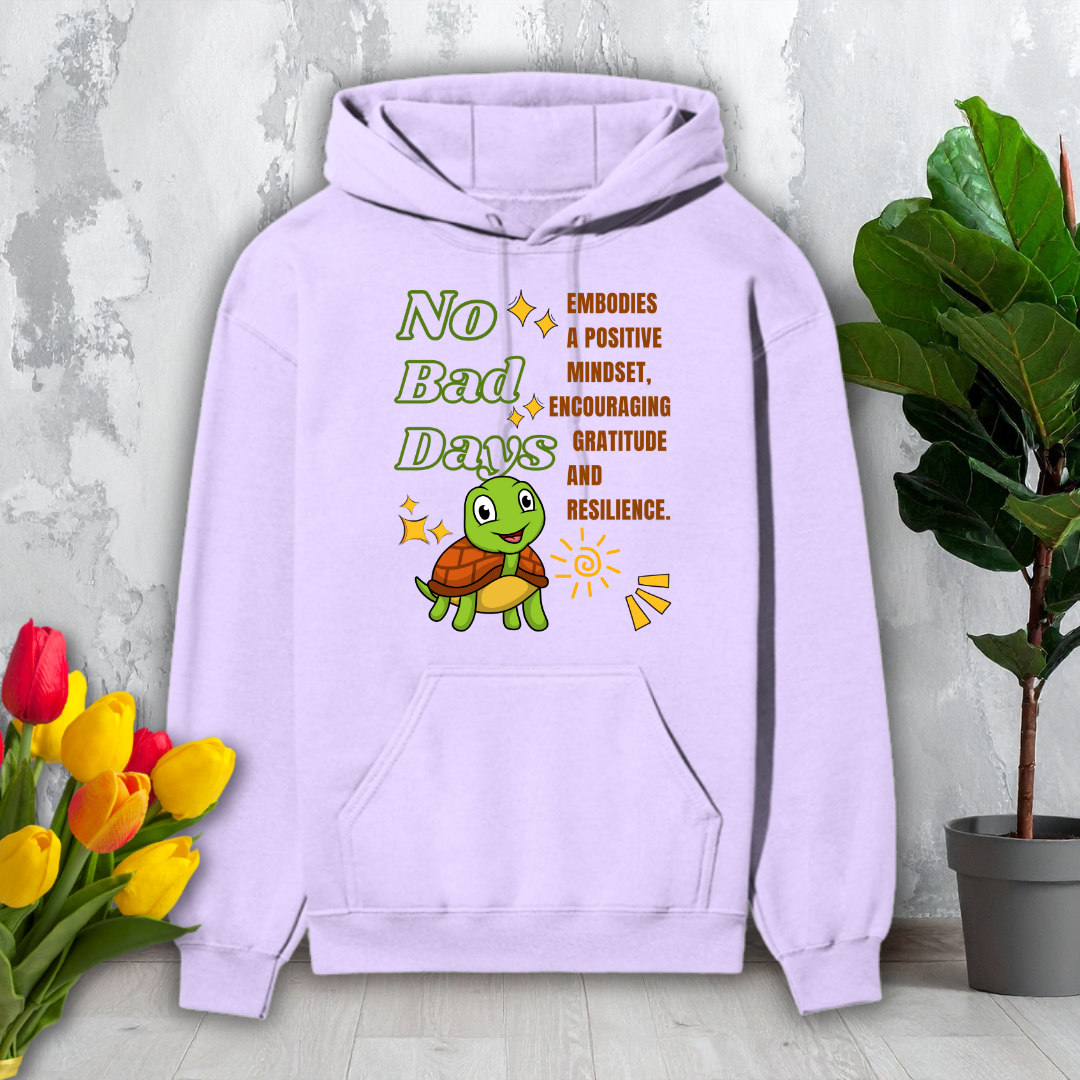 Purple hoodie with a turtle graphic and motivational text on a light gray surface with flowers and a plant.