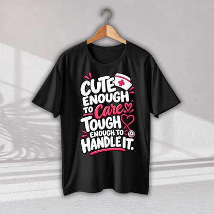 A black short-sleeve t-shirt hanging on a wooden hanger against a light gray wall. The shirt features a graphic print with the text 'CUTE ENOUGH TO Care, TOUGH ENOUGH TO HANDLE IT.