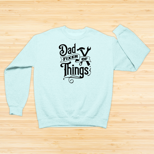 Mint sweatshirt with 'Dad Fixer of Things' text on a wooden surface