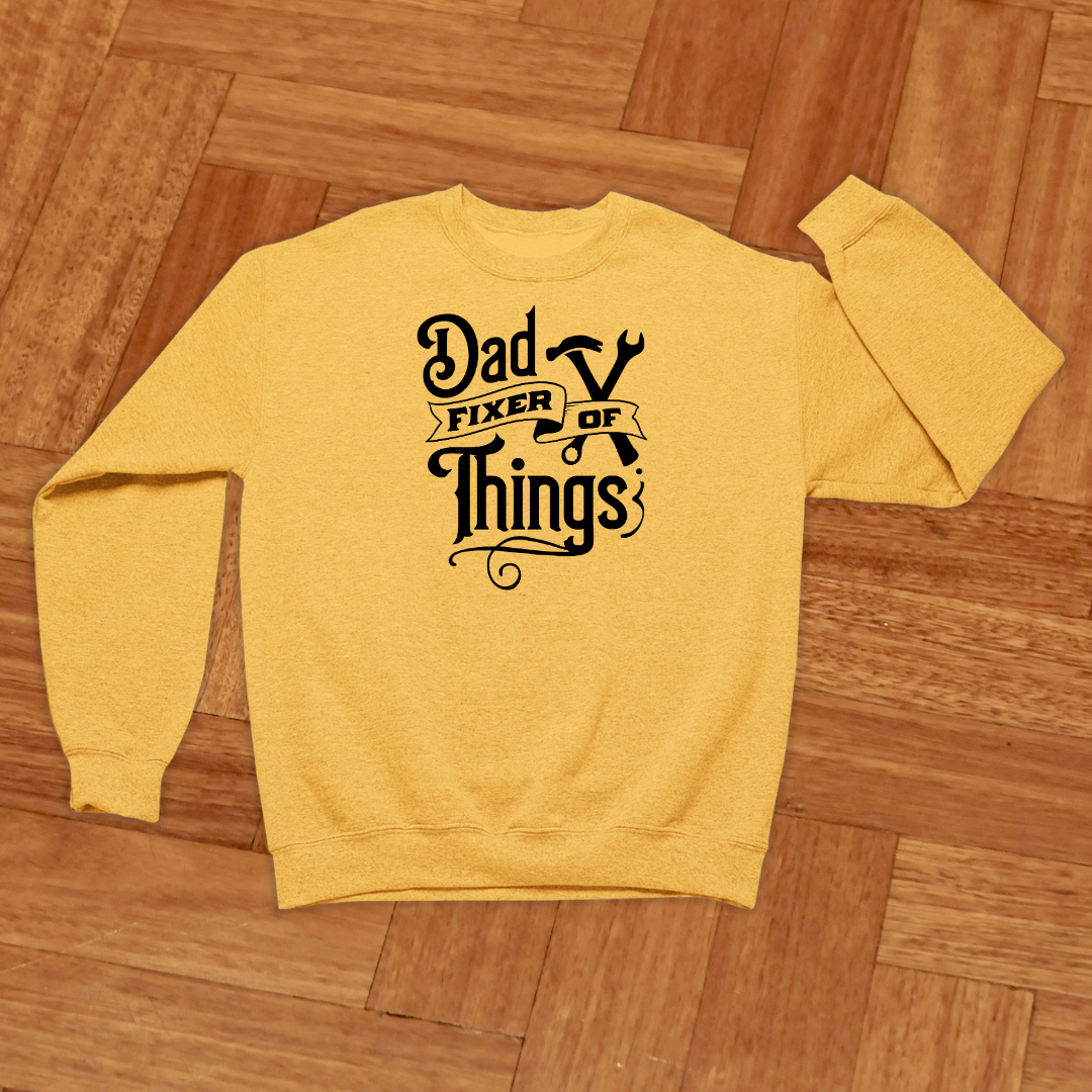 Yellow sweatshirt with 'Dad Fixer of Things' text on a wooden floor