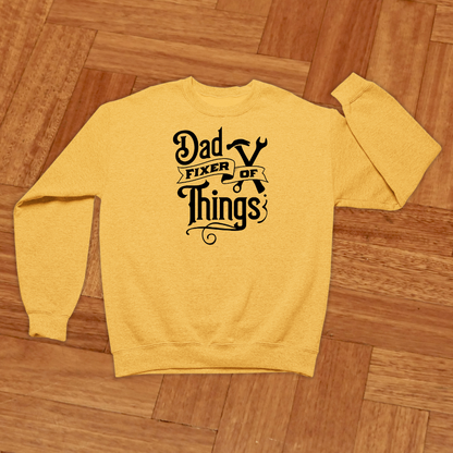 Yellow sweatshirt with 'Dad Fixer of Things' text on a wooden floor
