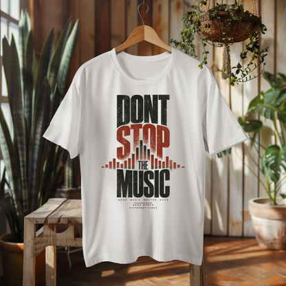 A white short-sleeve graphic T-shirt hanging on a wooden hanger in a rustic indoor setting with plants and wood paneling. The shirt features a large front graphic reading “DON'T STOP THE MUSIC” in black and distressed red lettering with a city skyline and soundwave design.