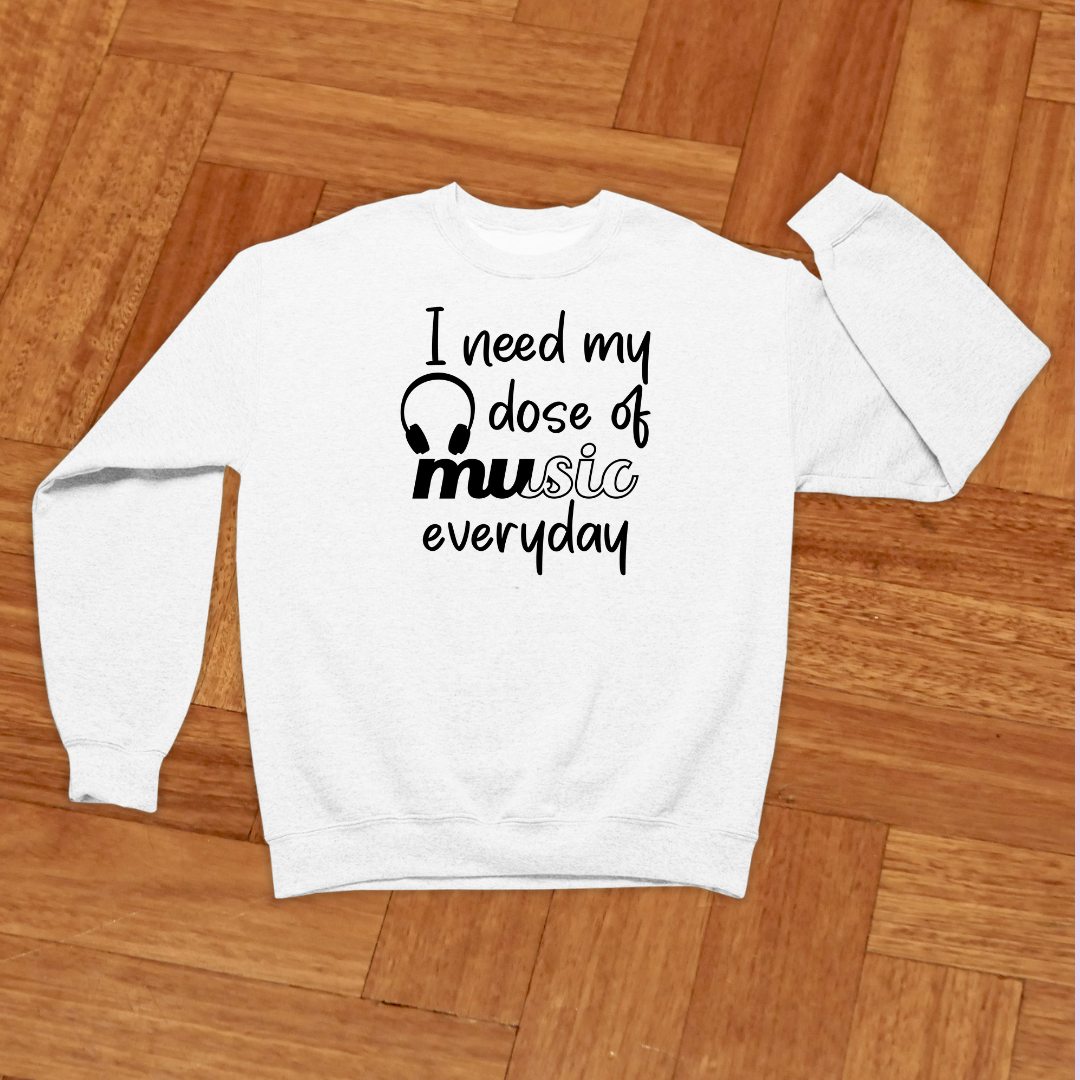 White sweatshirt with 'I need my dose of music everyday' text on a wooden floor
