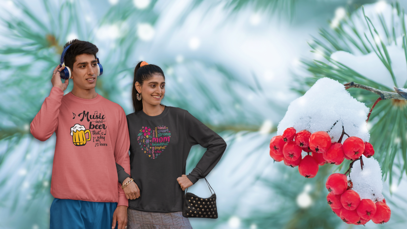 Two people wearing colorful shirts with text, standing in front of a snowy background with red berries.