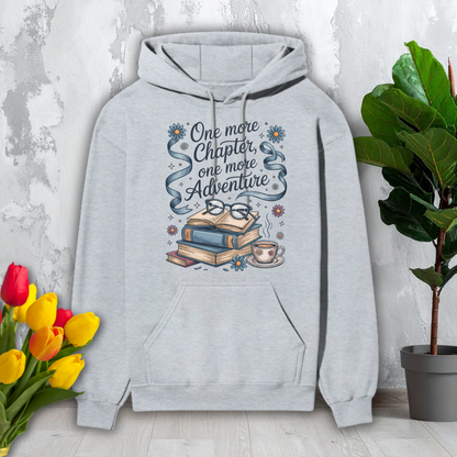 Gray hoodie with book-themed design and text on a light gray background with flowers and a plant.