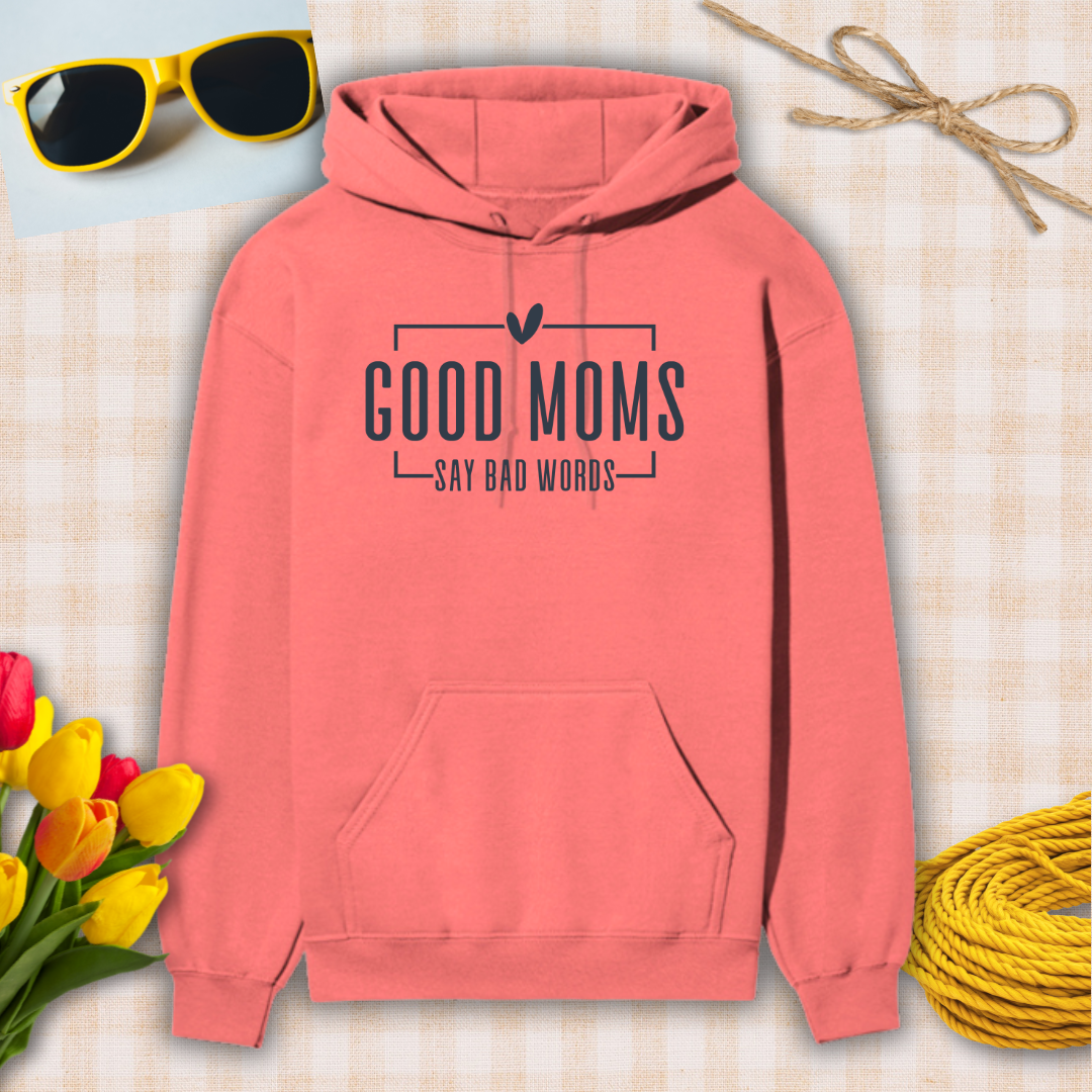 Coral hoodie with 'Good moms say bad words' text on a checkered background with sunglasses, tulips, and twine.