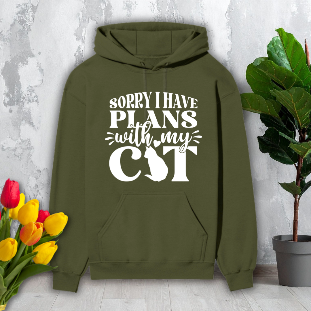 Green hoodie with 'Sorry I have plans with my cat' text on a light gray background with flowers and a plant.
