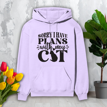 Light purple hoodie with text 'Sorry I have plans with my cat' on a light gray background with flowers and a plant.