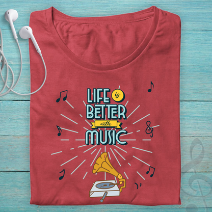 A folded red t-shirt with a retro graphic that reads 'LIFE IS BETTER with MUSIC' in teal and yellow, surrounded by musical notes and a gramophone illustration, displayed on a light blue wooden background with white earbuds.