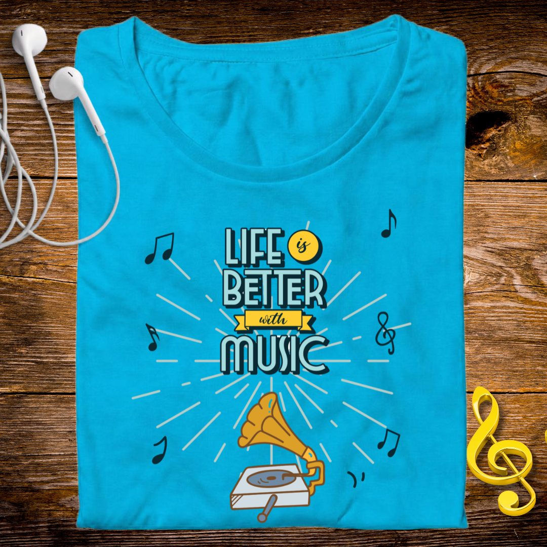A folded bright turquoise blue t-shirt with a graphic that reads 'LIFE IS BETTER WITH MUSIC' in stylized lettering, surrounded by musical notes, a gramophone illustration, and a small yellow smiley face. The shirt is laid flat on a rustic wooden surface with white earbuds on the left and a yellow treble clef on the right.