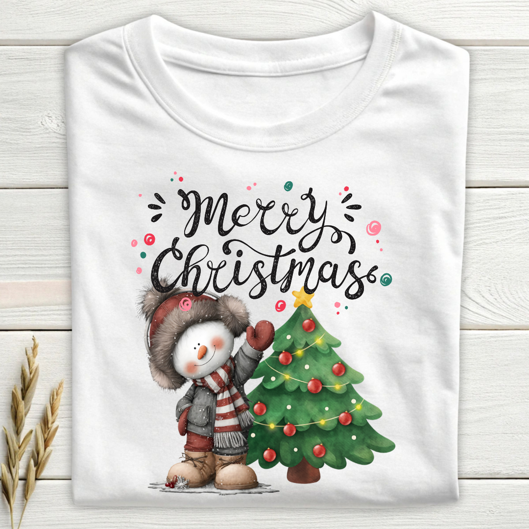 White t-shirt with a snowman and Christmas tree design on a wooden surface