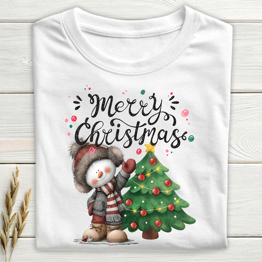 White t-shirt with a snowman and Christmas tree design on a wooden surface