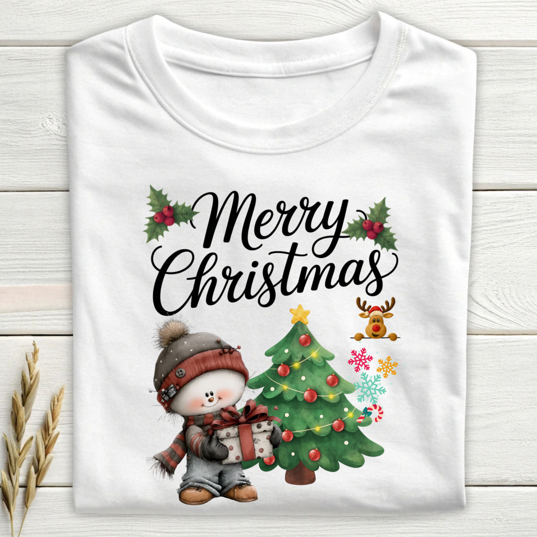 White t-shirt with Christmas design featuring a snowman and tree on a wooden surface.