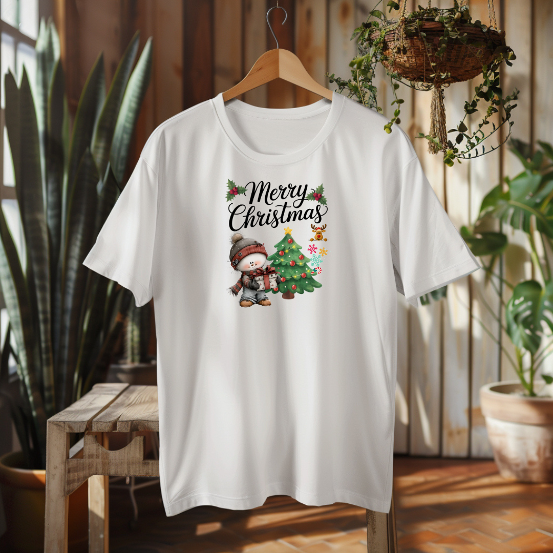 White t-shirt with Christmas design featuring a child and tree, hanging in a room with plants.