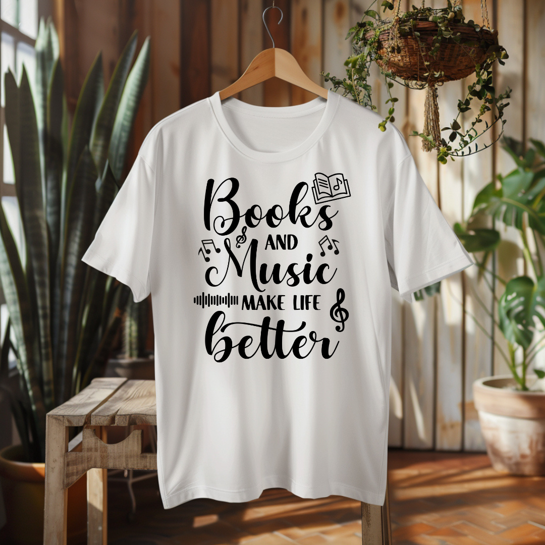 A white short-sleeve graphic T-shirt hanging on a wooden hanger against a rustic indoor backdrop with plants and wood paneling. The shirt features a black decorative typographic design on the front reading, 'We can't always choose the music life plays for us but we can choose how we dance to it.