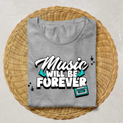 A folded heather gray t-shirt with a retro graphic reading 'Music WILL BE FOREVER' in white and black with teal accents, displayed on a round woven wicker tray against a light gray background.