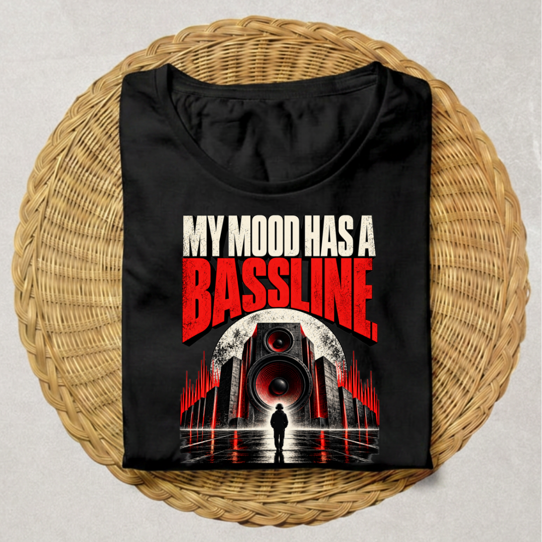 A black short-sleeve t-shirt with a graphic print reading 'MY MOOD HAS A BASSLINE' in white and red, displayed flat on a round woven wicker mat against a light gray background.