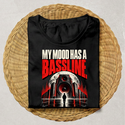 A black short-sleeve t-shirt with a graphic print reading 'MY MOOD HAS A BASSLINE' in white and red, displayed flat on a round woven wicker mat against a light gray background.