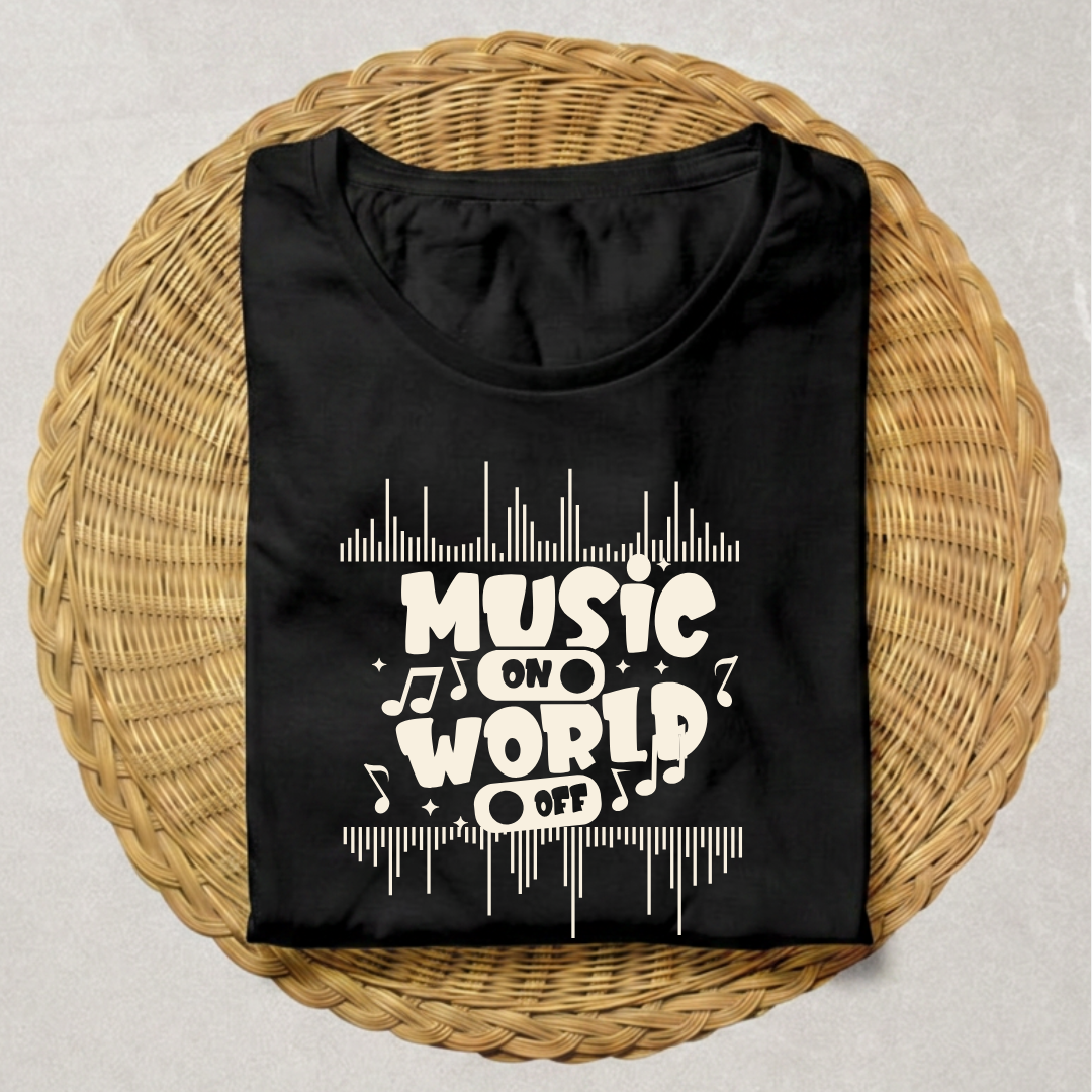 A folded black t-shirt with a white graphic reading 'MUSIC ON WORLD OFF' surrounded by musical notes and equalizer lines, displayed on a round woven wicker tray over a light gray background.