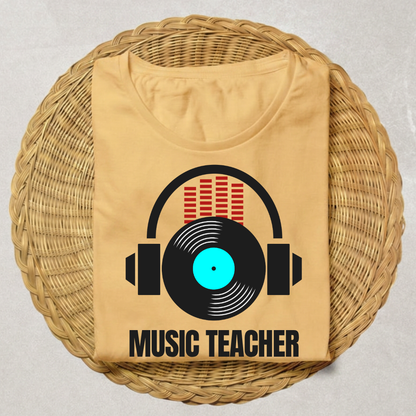 A beige t-shirt folded and displayed on a round woven straw mat. The shirt features a graphic of black headphones with a vinyl record, red equalizer bars, and the text 'MUSIC TEACHER' in black.