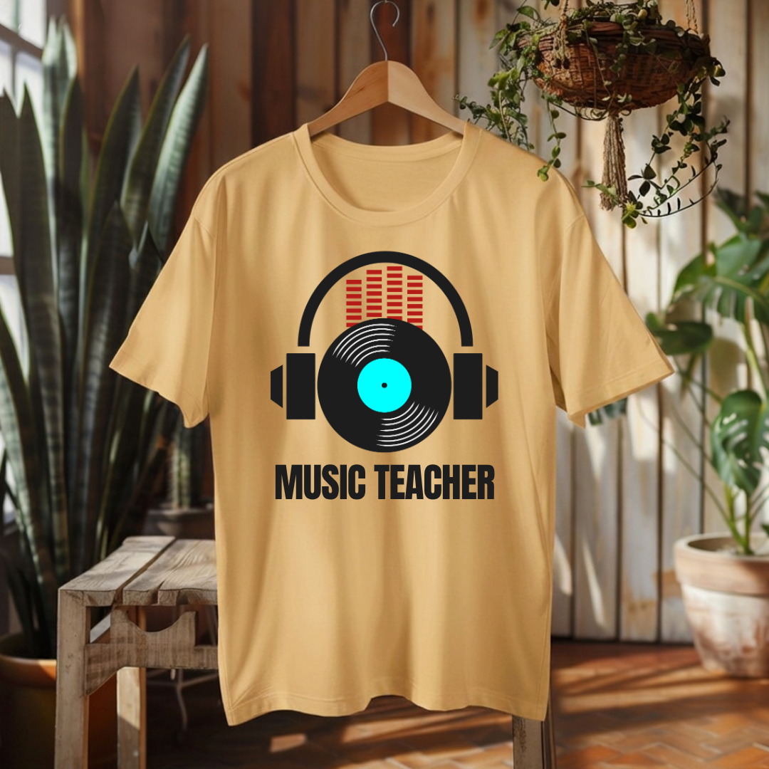 A light beige graphic t-shirt hanging on a wooden hanger against a rustic wood-paneled wall with plants. The shirt features a graphic of black headphones over a vinyl record with a bright cyan center and red audio bars, with the text 'MUSIC TEACHER' printed below in black.