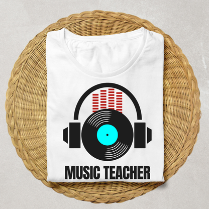 A folded white t-shirt displayed on a round woven straw mat. The shirt features a graphic of black headphones with a vinyl record and red equalizer bars, with the text 'MUSIC TEACHER' printed below in black.