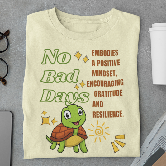 Beige t-shirt with a turtle graphic and motivational text on a gray surface.