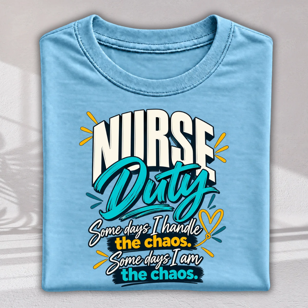 A folded light blue t-shirt with a graphic print that reads 'NURSE Duty' and a humorous quote below, displayed against a neutral gray background with soft shadow details.