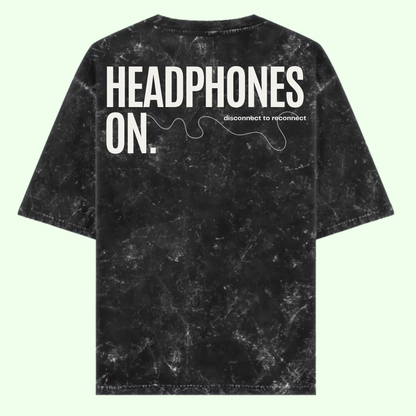 Black tie-dye t-shirt with 'HEADPHONES ON.' text on a light green background