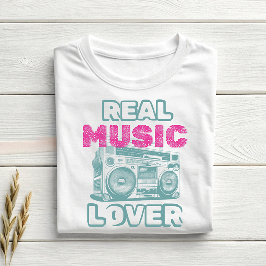 Folded white t-shirt with 'Real Music Lover' graphic on a wooden surface