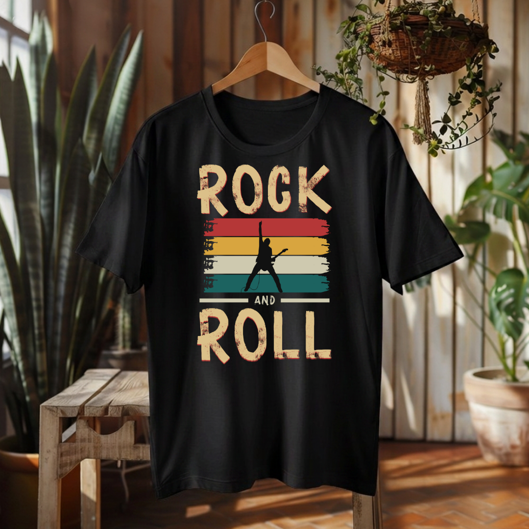 A black short-sleeve graphic T-shirt hanging on a wooden hanger in a rustic indoor setting with plants and wood paneling. The shirt features a distressed retro-style graphic reading 'ROCK AND ROLL' with a vertical striped background and a black silhouette of a guitar player.