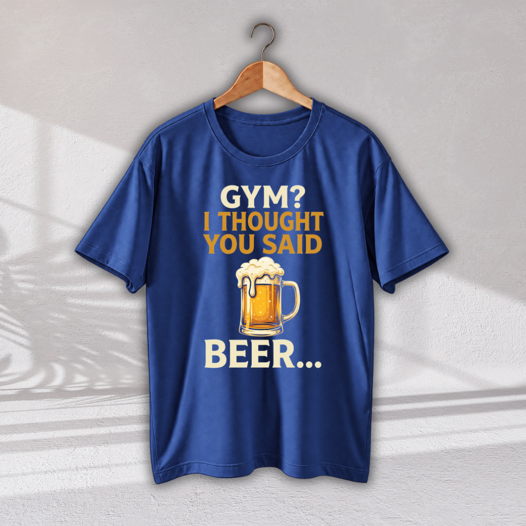 A royal blue short-sleeve t-shirt hanging on a wooden hanger against a light gray wall. The shirt features a graphic print with the text 'GYM? I THOUGHT YOU SAID BEER.