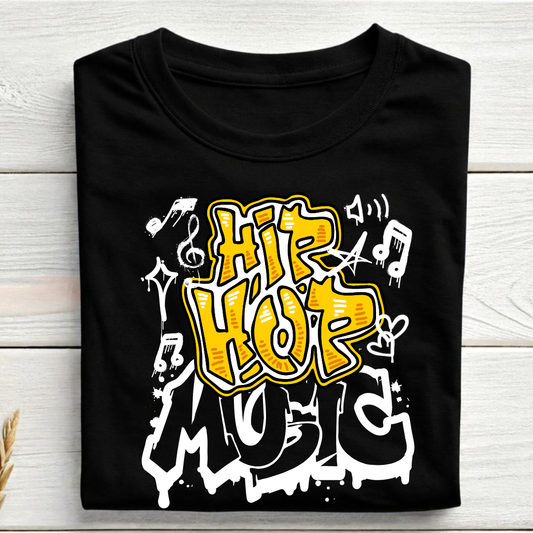 A black short-sleeve T-shirt laid flat on a light wood plank background, featuring a large graffiti-style graphic that reads 'HIP HOP MUSIC' in yellow, white, and black, with musical notes and symbols.