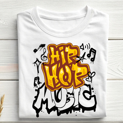 A folded white t-shirt with a colorful graphic print reading 'HIP HOP MUSIC' in orange, yellow, black, and white graffiti-style lettering, displayed on a light wood plank background.