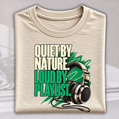 A folded beige crewneck t-shirt featuring a graphic print with the text 'QUIET BY NATURE LOUD BY PLAYLIST.' in cream and bright green, alongside a graphic of black and silver over-ear headphones on a gray background.