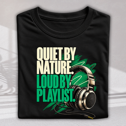 A folded black t-shirt with a graphic print that reads 'QUIET BY NATURE LOUD BY PLAYLIST.' in cream and green text, featuring an illustration of over-ear headphones on a light gray background.