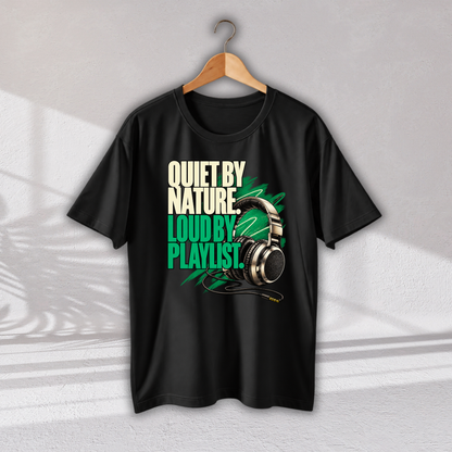 A black short-sleeve graphic T-shirt hanging on a wooden hanger against a light gray wall. The shirt features a bold graphic print with the text 'QUIET BY NATURE, LOUD BY PLAYLIST.