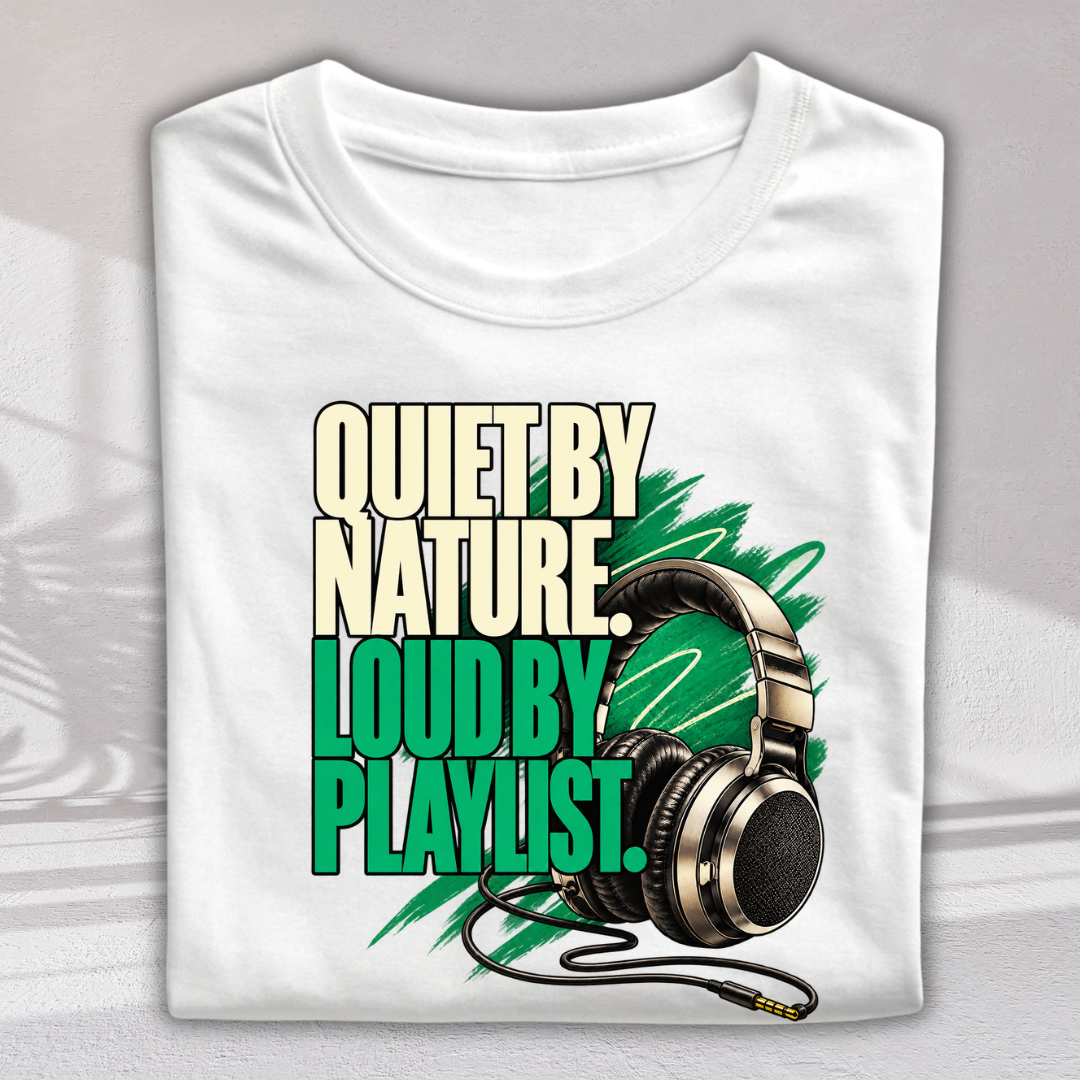 A folded white t-shirt with a graphic print that reads 'QUIET BY NATURE LOUD BY PLAYLIST.' in beige and green text, featuring a pair of black and gold headphones over green paint strokes.
