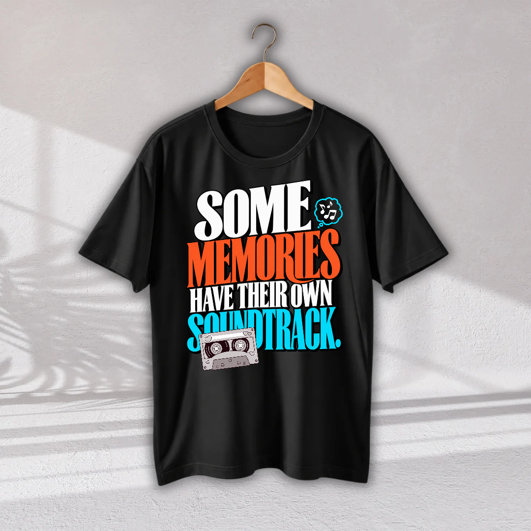 A black short-sleeve t-shirt hanging on a wooden hanger against a light gray wall. The shirt features a colorful retro graphic with the text 'SOME MEMORIES HAVE THEIR OWN SOUNDTRACK.